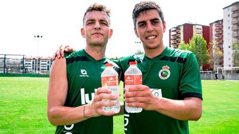 Los jugadores Íñigo Vicente (izquierda), centrocampista, e Íñigo Sainz (derecha), capitán del equipo, posan con Agua de Solares